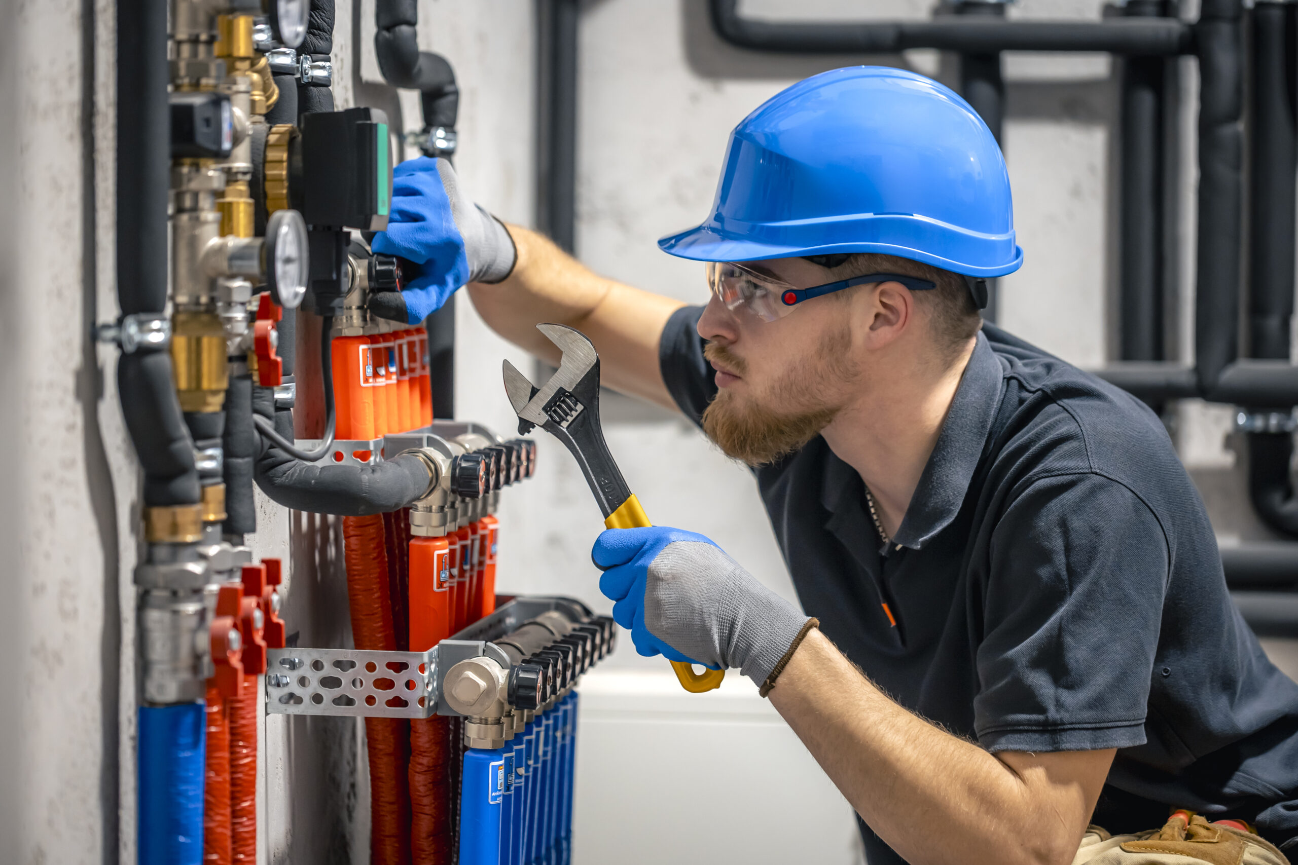 The technician checking the heating system in the boiler room. The technician checking the heating system in the boiler room. Adjusting heating valves in a residential building. A plumbing and heating technician works.
